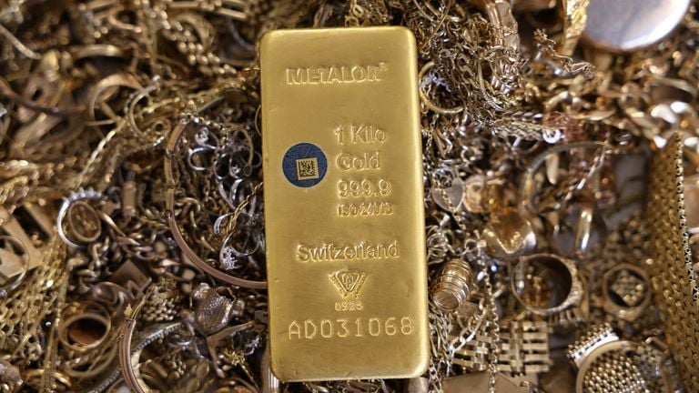 Photograph of a 1kg gold bar among jewelry &mdash; shows physical bullion and underscores why geopolitical risk (Middle East) and Fed-rate expectations can move demand and price for gold.